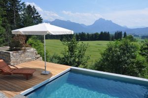 Living Pool mit Sonnenschirm und Blick auf die Allgäuer Berge
